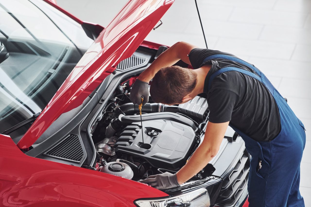 Top view of male worker in uniform that repairs red automobile.jpg