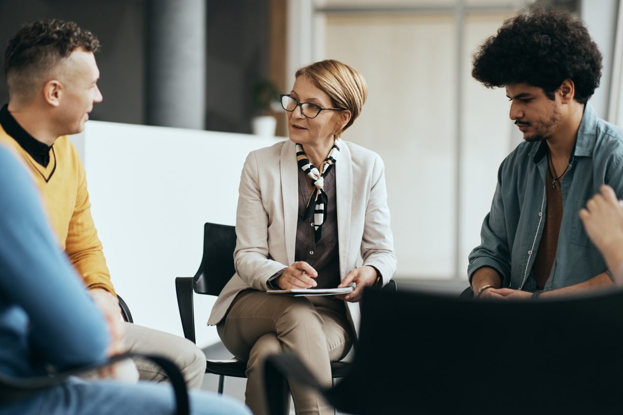 Mature therapist talking to participants of group therapy at mental health center .jpg
